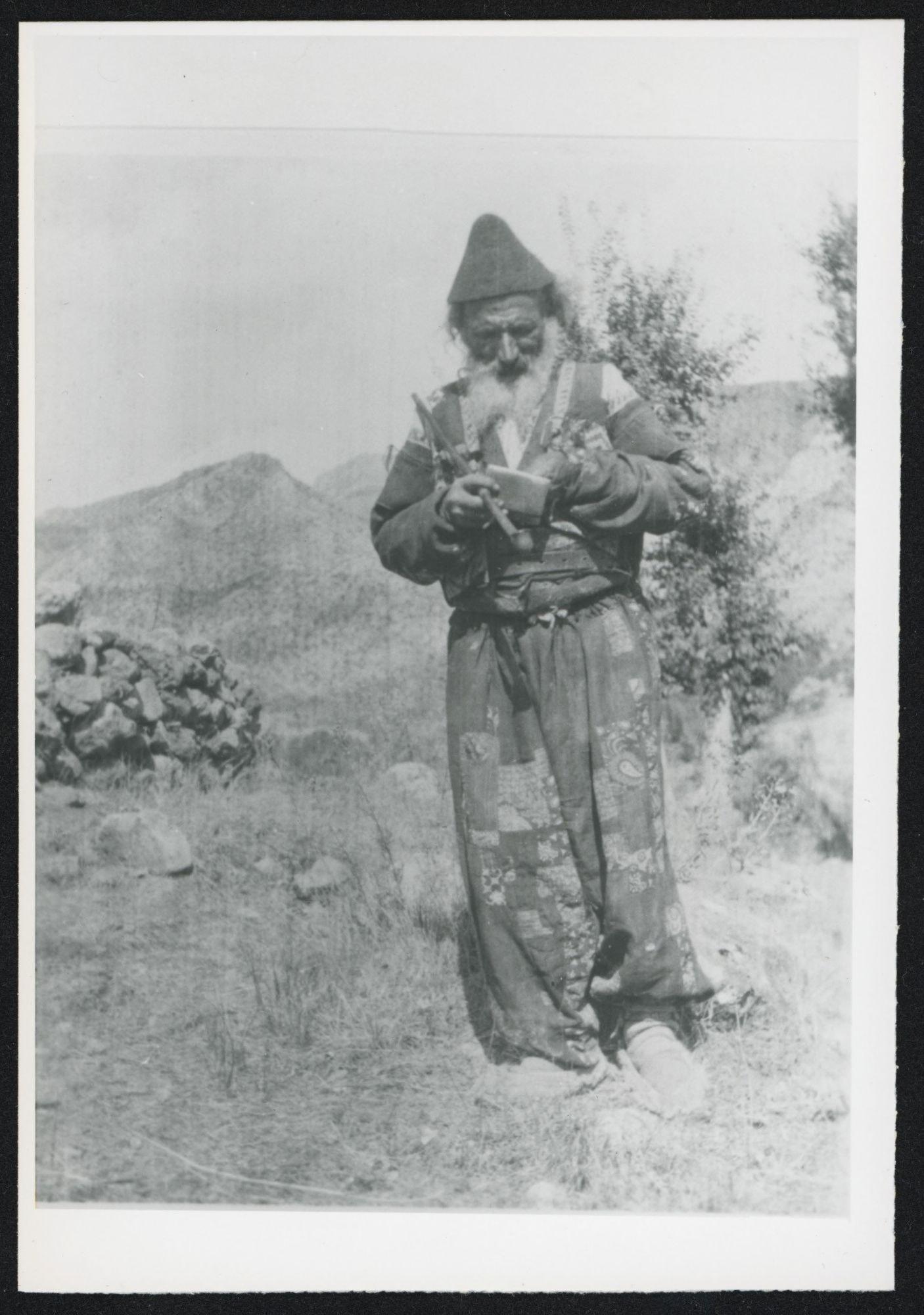 Mountain man filling his pipe, possibly Assyrian