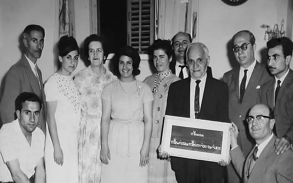 Syriac community group with a Syriac-script sign, Aleppo, 1963