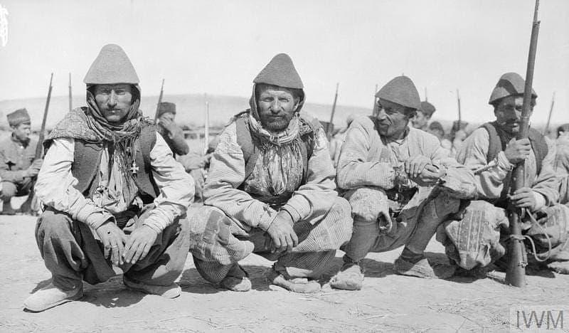Four Jilu Assyrian recruits crouching at a training camp, Hamadan