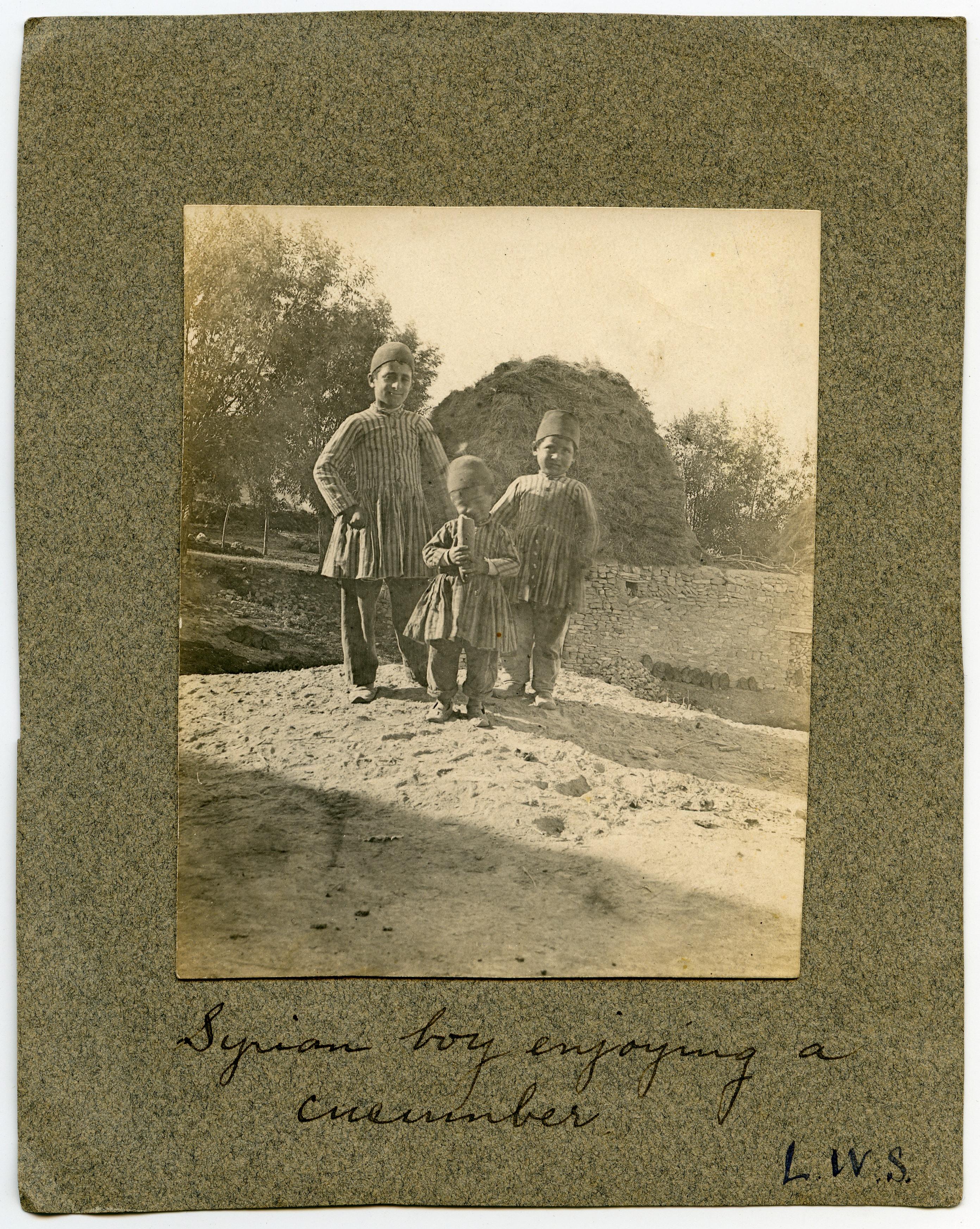 Assyrian boy eating a cucumber, with two other children, Urmia region
