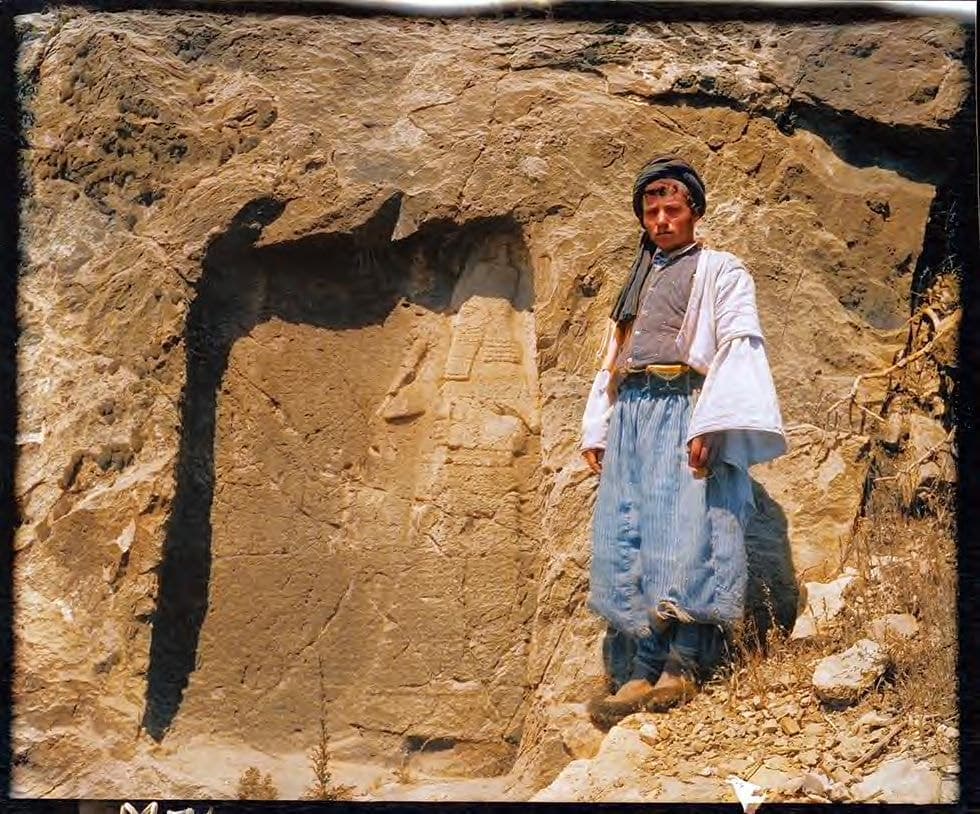 Shim'un, brother of Kasha Mattai, beside an Assyrian rock relief