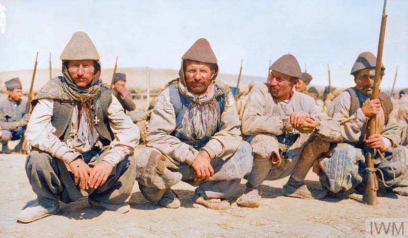 Four Jilu Assyrian recruits crouching at a training camp, Hamadan